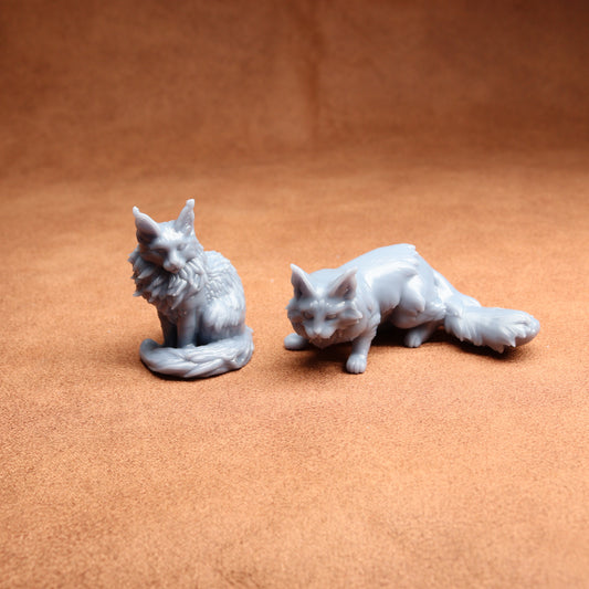 Two gray ceramic fox figurines on a brown surface