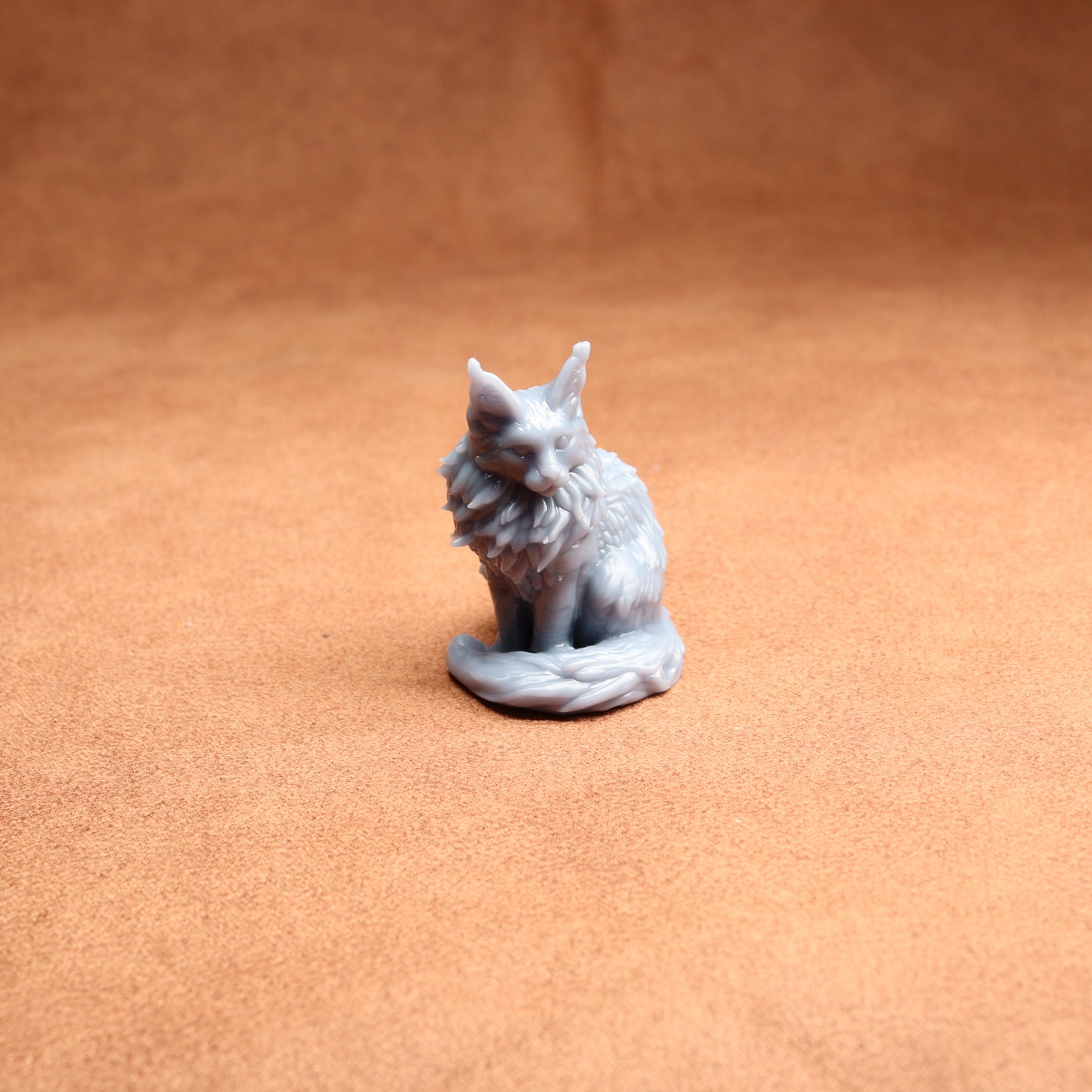 Small gray cat figurine on a brown surface