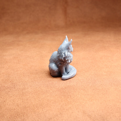 Small gray figurine of a cat on a brown surface