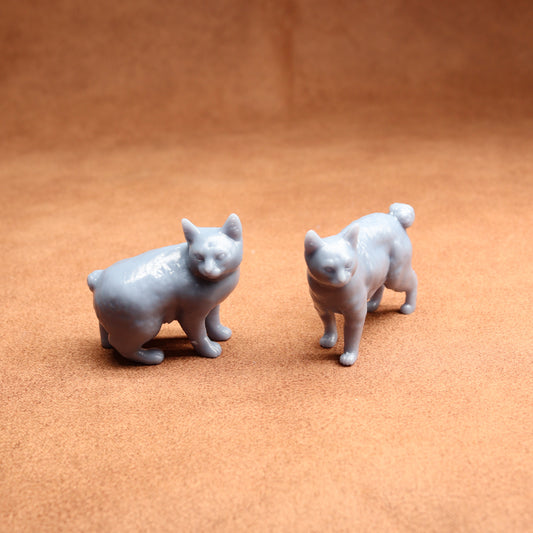 Two small gray cat figurines on a brown surface
