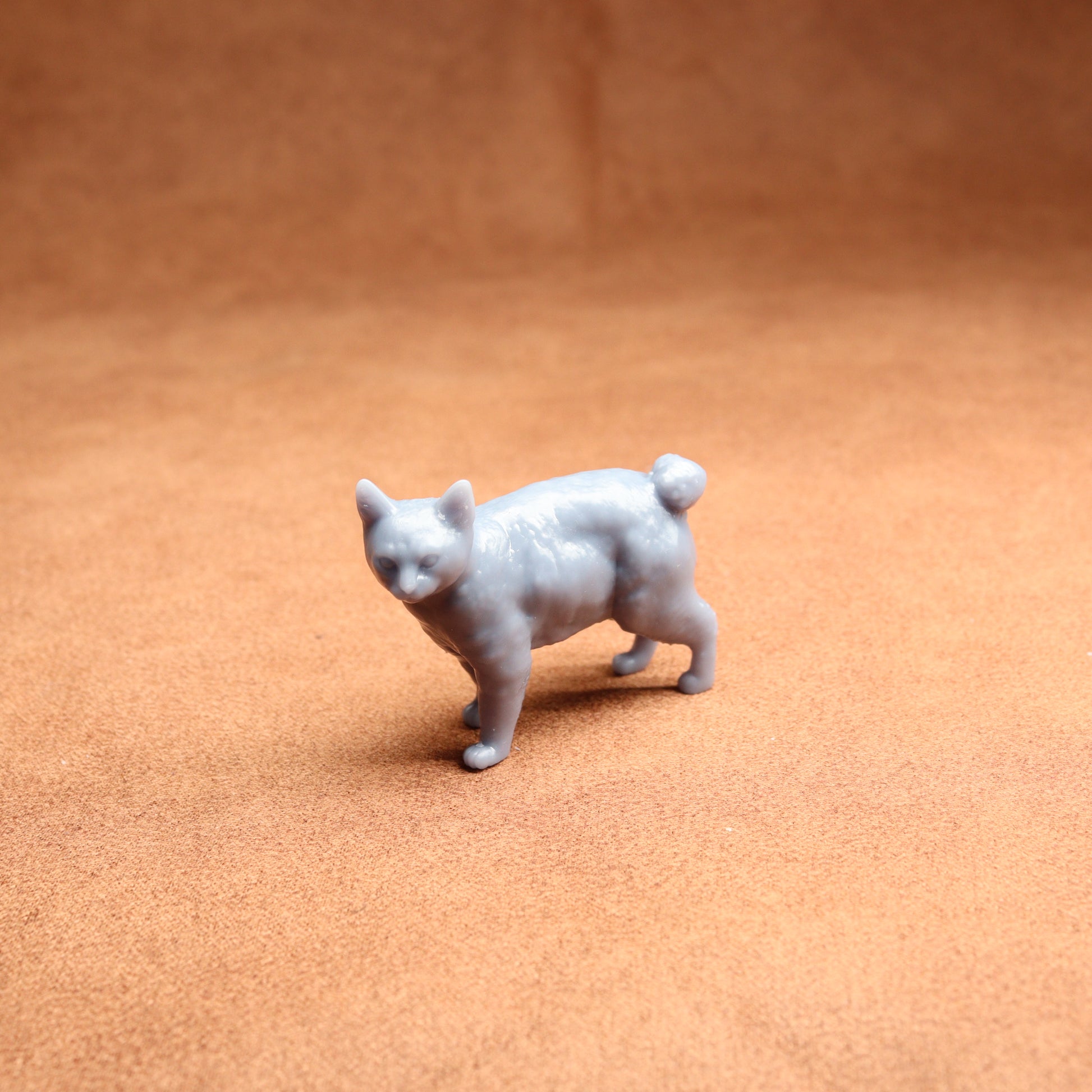 Small gray cat figurine on a brown surface