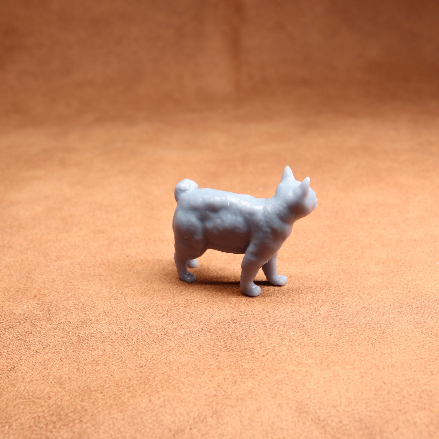 Small gray dog figurine on a brown surface