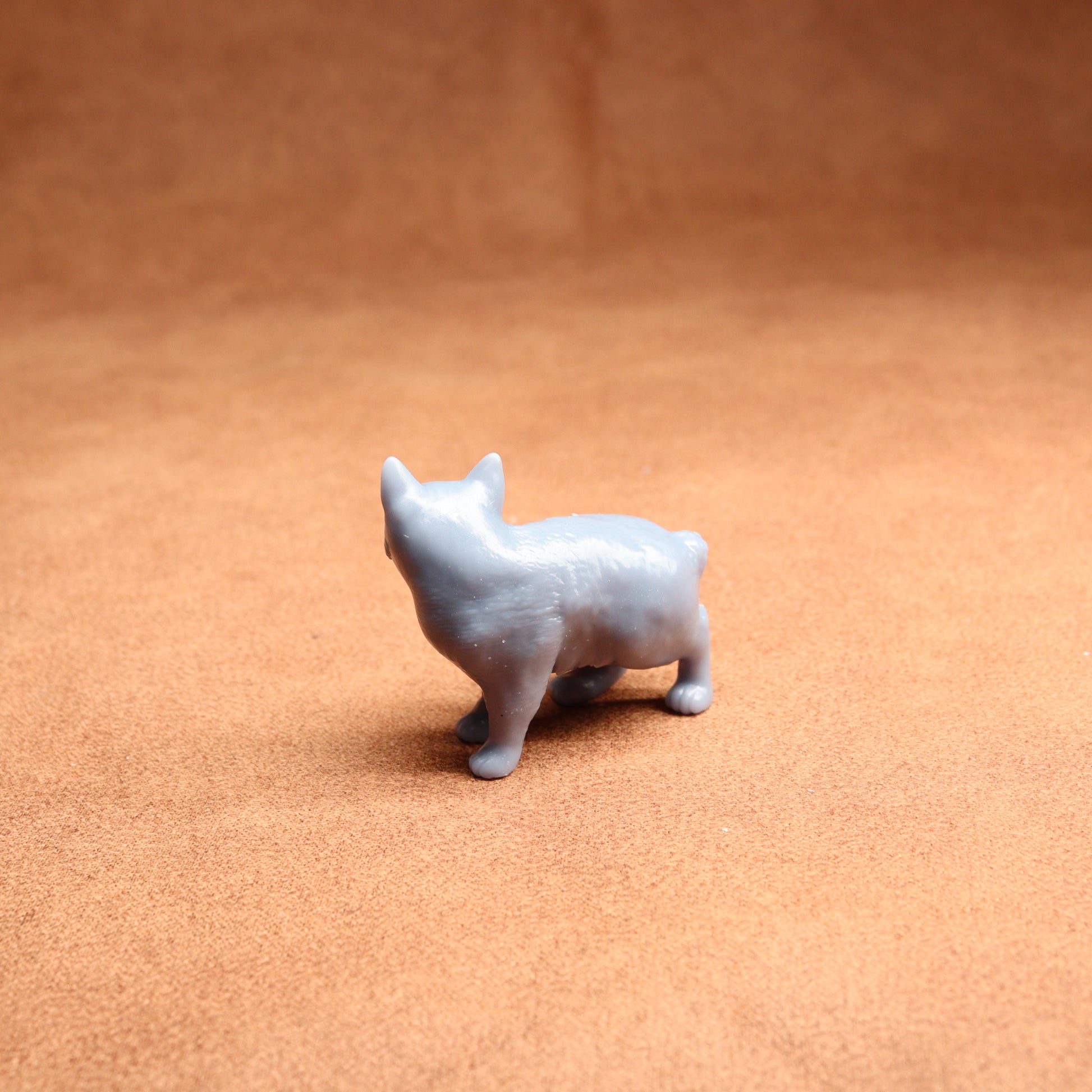Small gray dog figurine on a brown surface