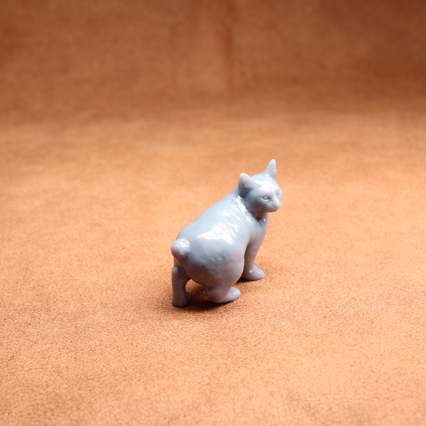 Small gray cat figurine on a brown surface