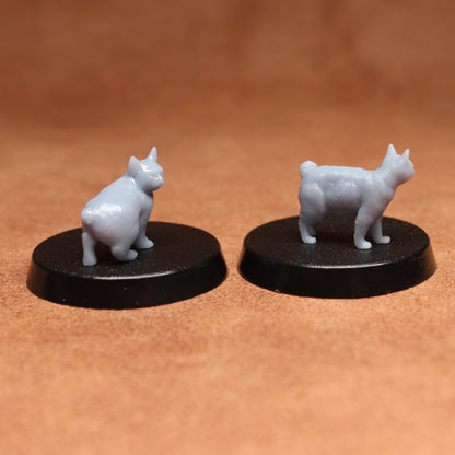 Two white cat figurines on black bases against a brown background
