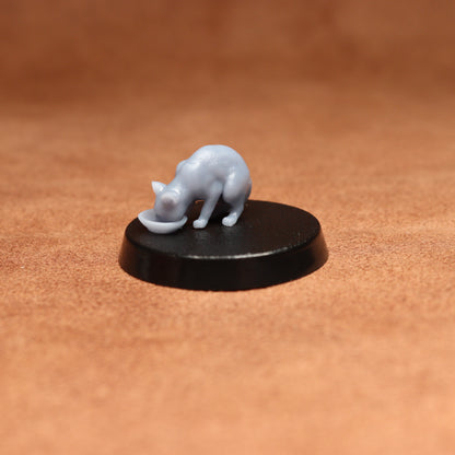grey resin miniature cat figure on a black base with a brown background