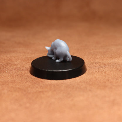 grey resin miniature cat figure on a black base with a brown background