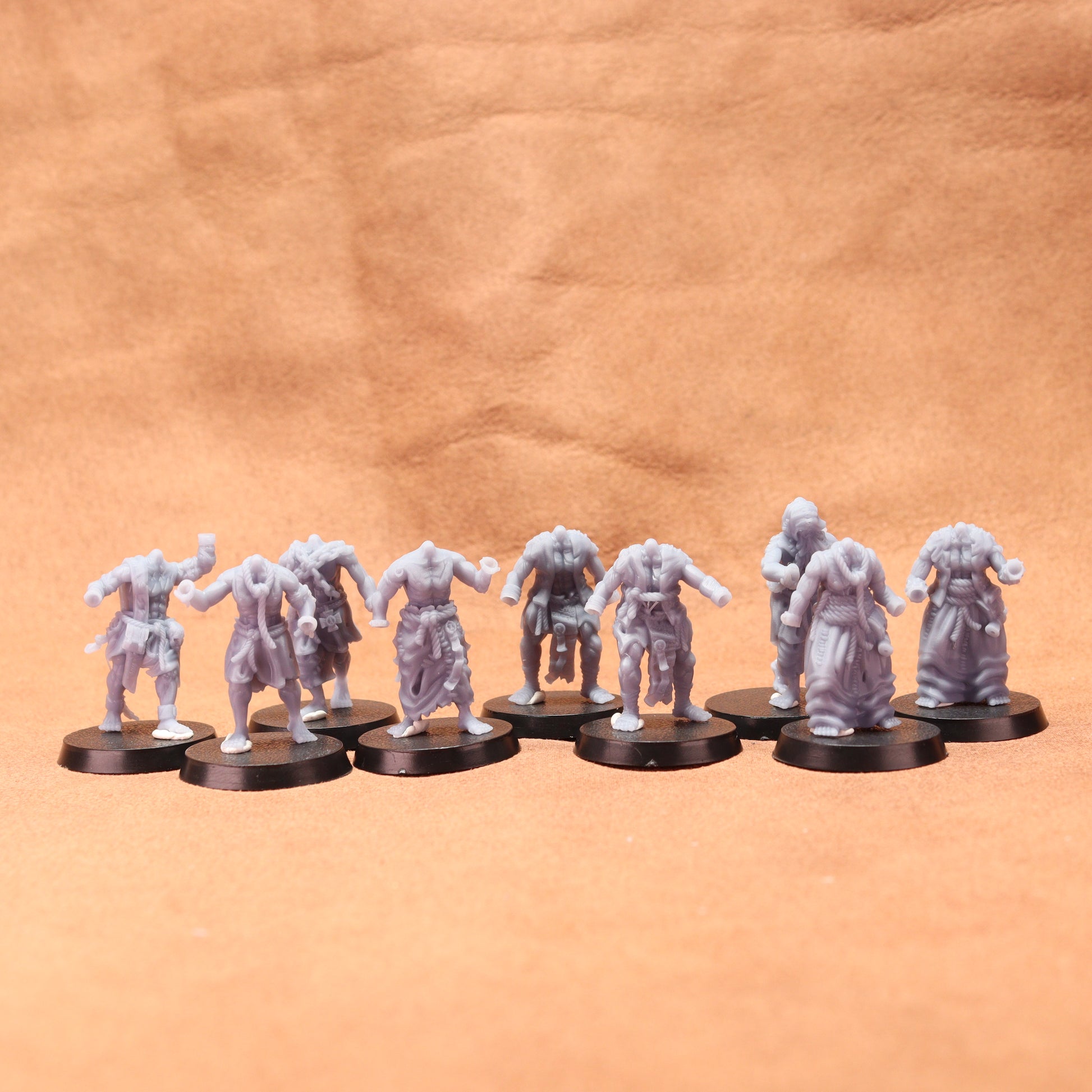 Row of gray miniature figures on black round bases against a brown leather background