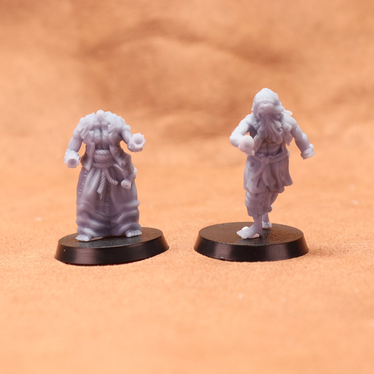 Two miniature figures on round bases against a brown background