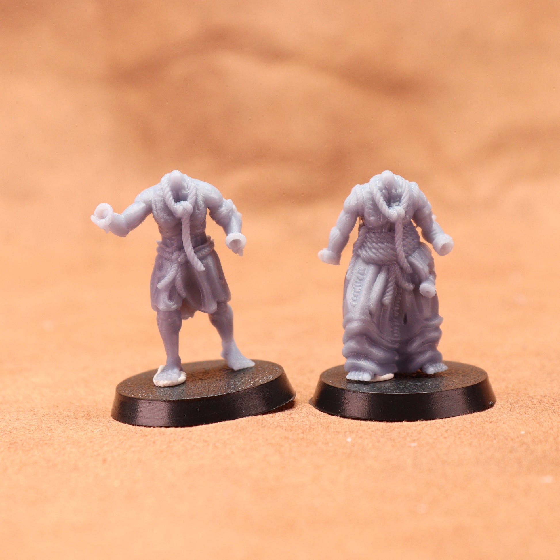 Two miniature figures on round bases against a brown background