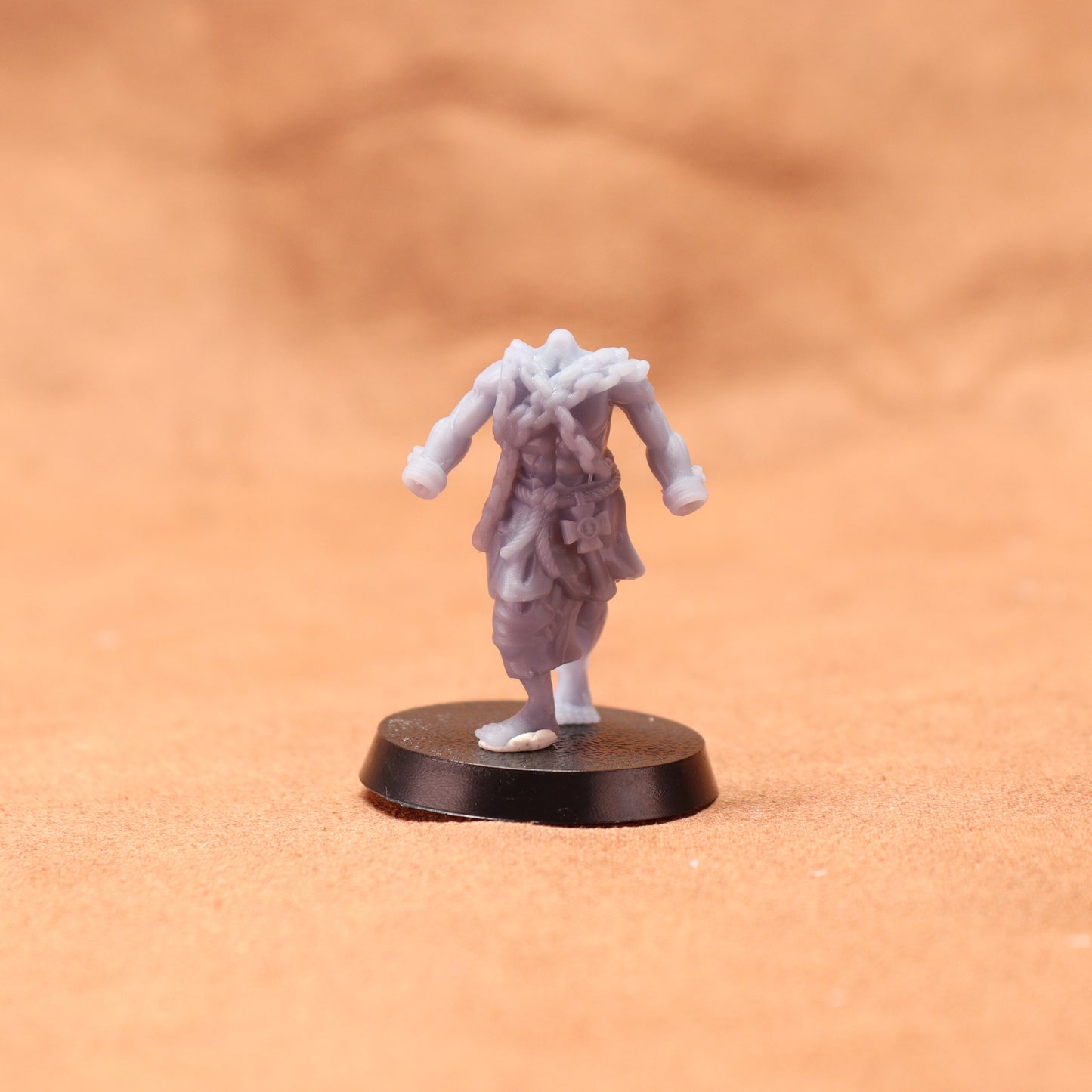 Miniature figurine on a round base against an orange background