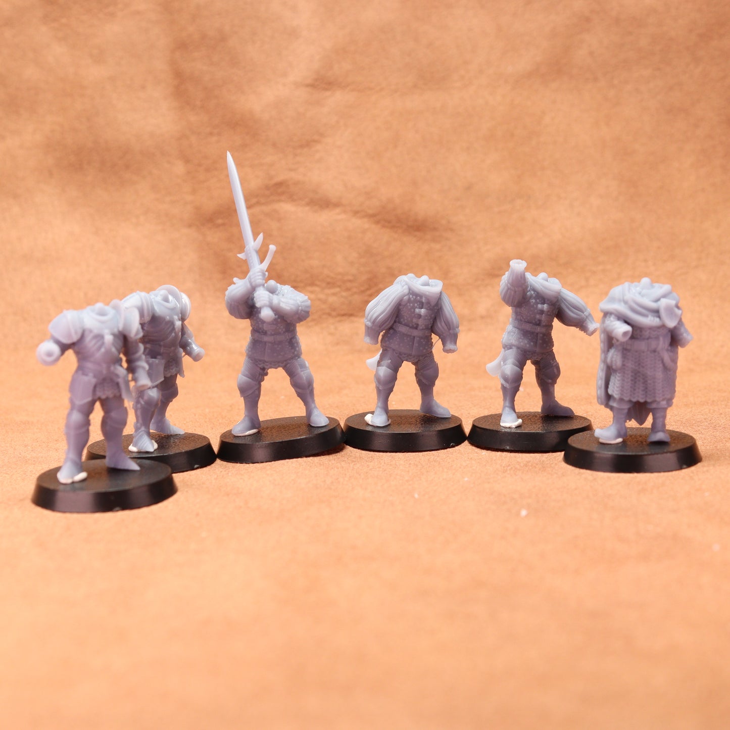Set of six gray miniature figures on black bases against a brown background