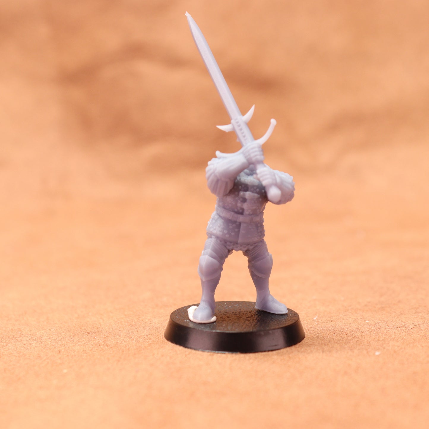 Miniature figurine of a warrior holding a sword on an orange background
