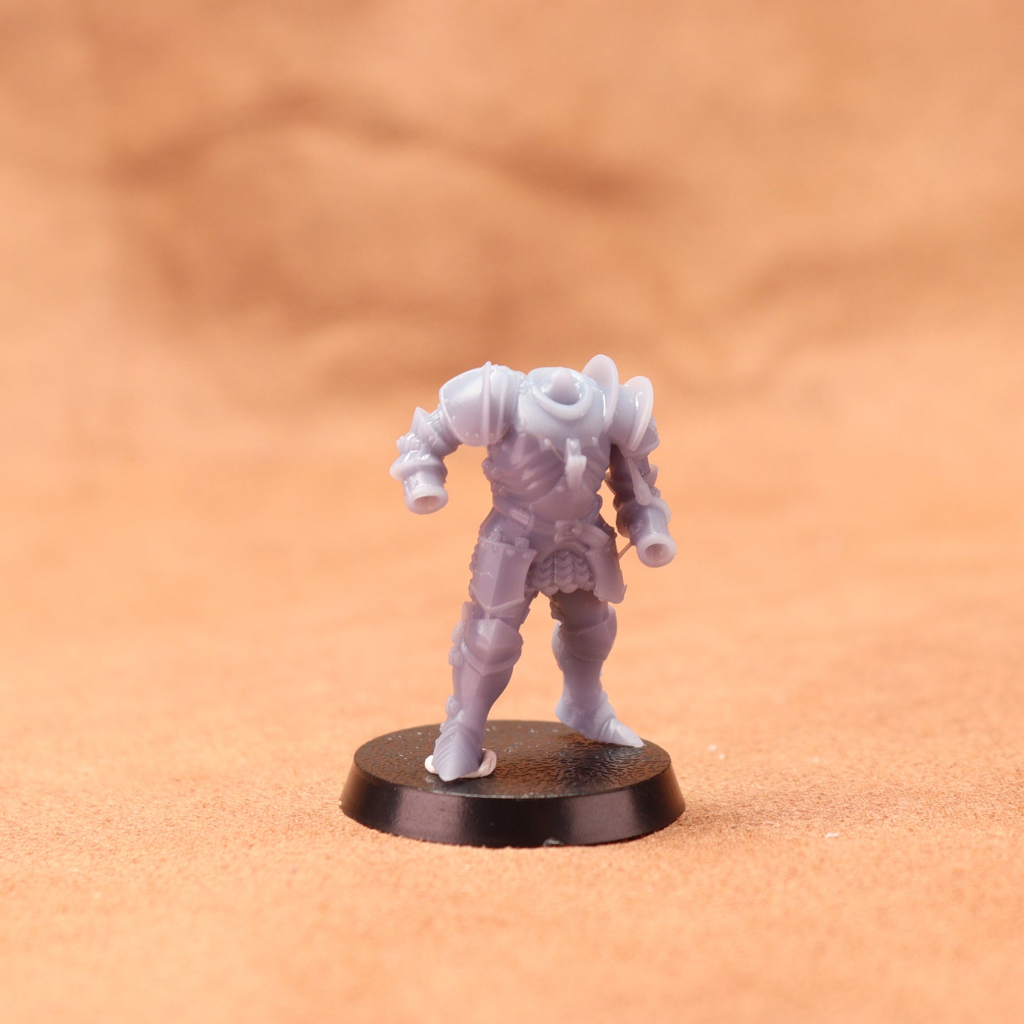 Miniature figurine on a round black base against an orange background