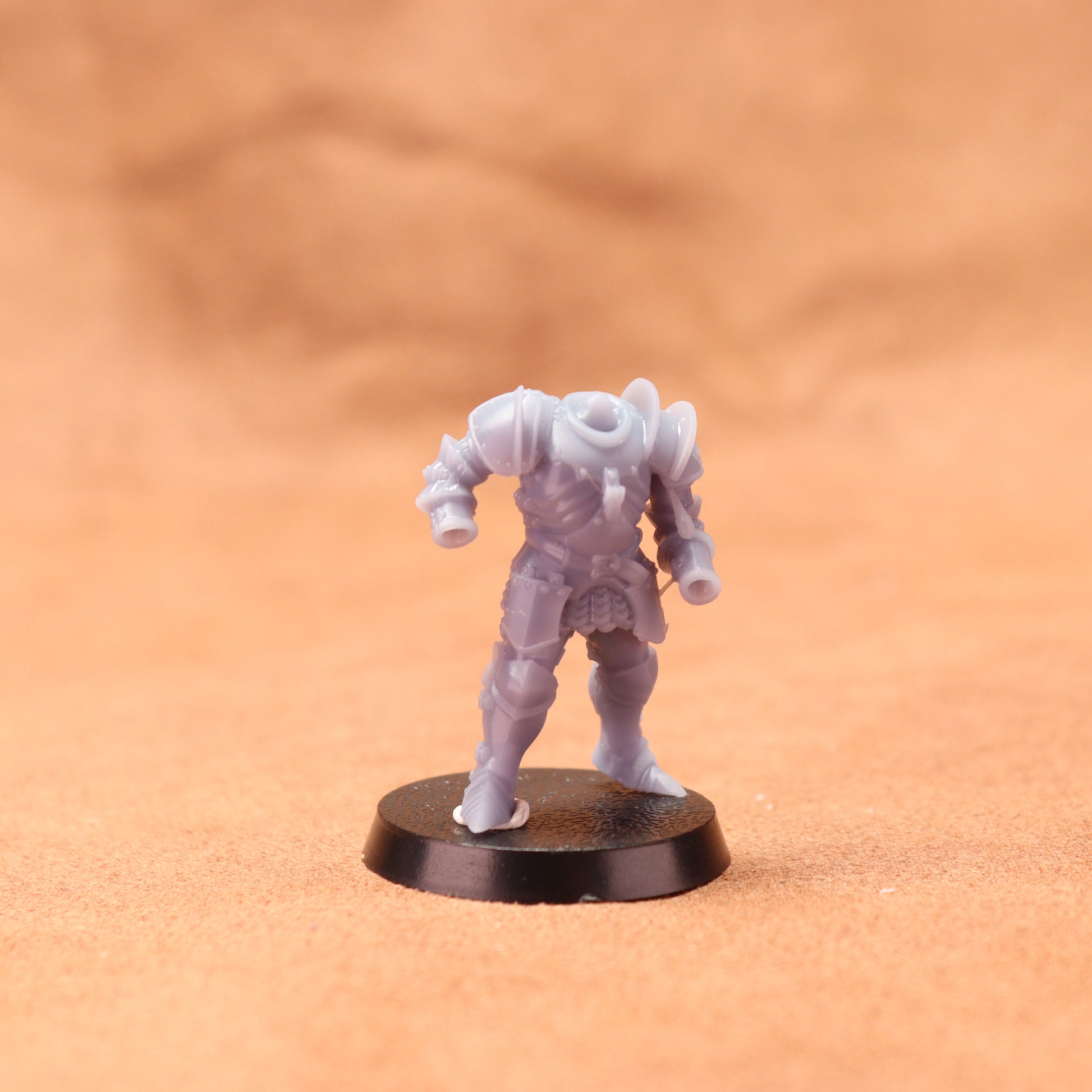 Miniature figurine on a round black base against an orange background