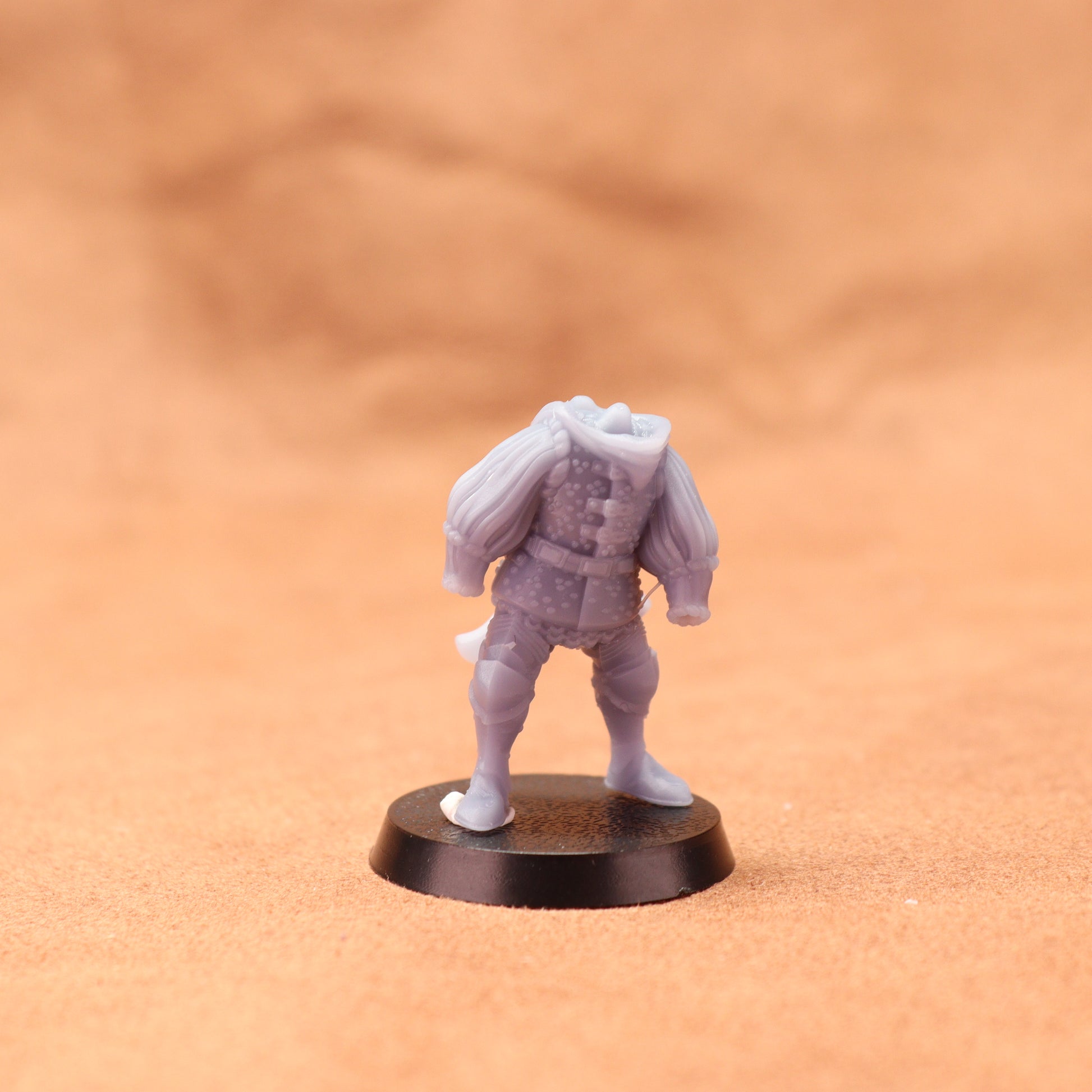 Gray miniature figure on a black base against an orange background