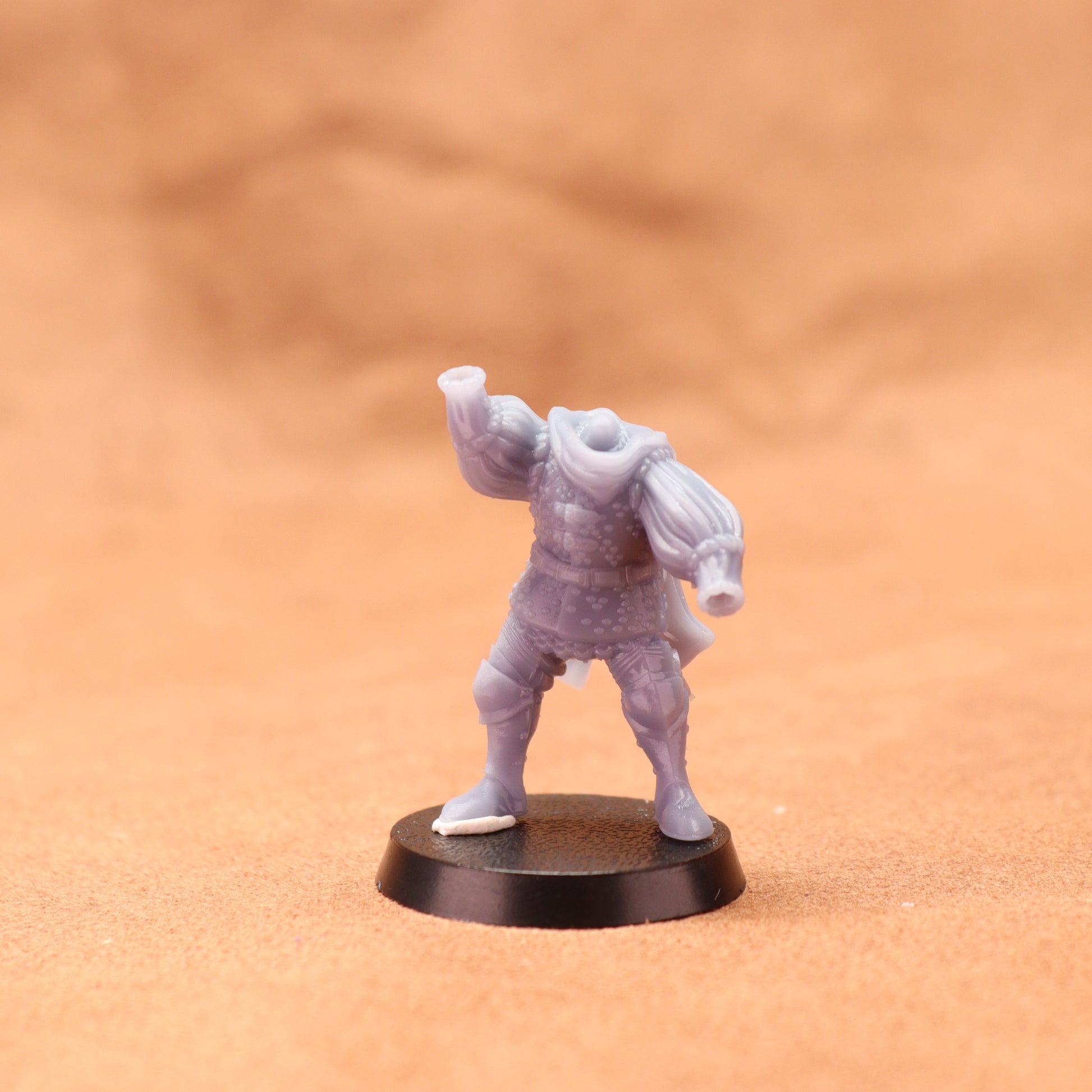 Gray miniature figure on a black base against a brown background