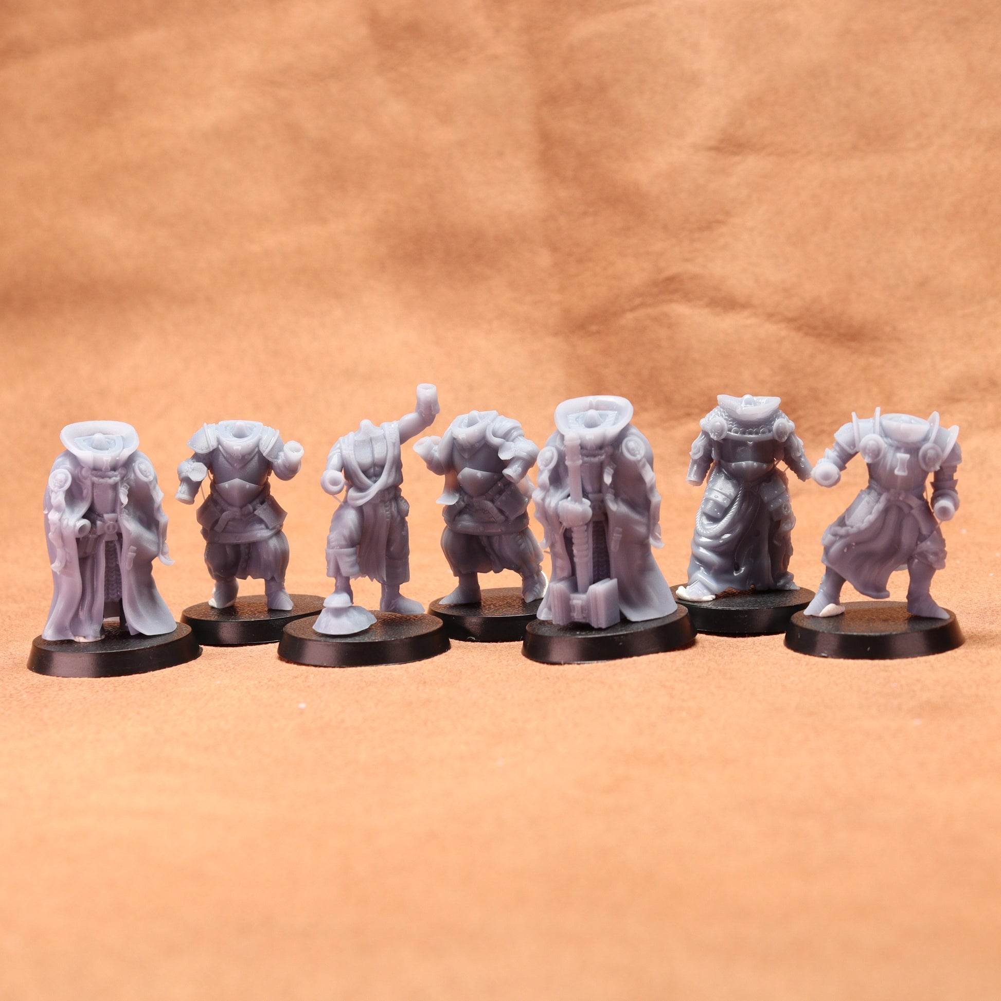 Set of eight gray miniature figures on black stands against a brown background