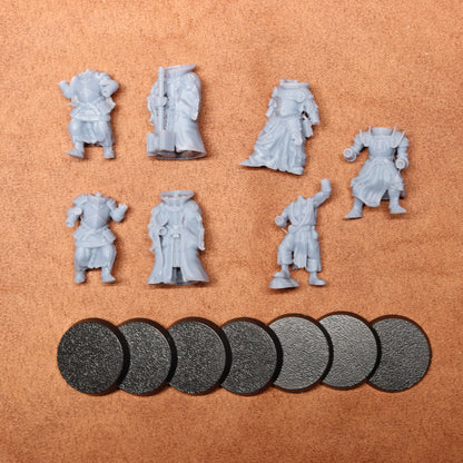 Set of gray miniature figures and round bases on a brown surface