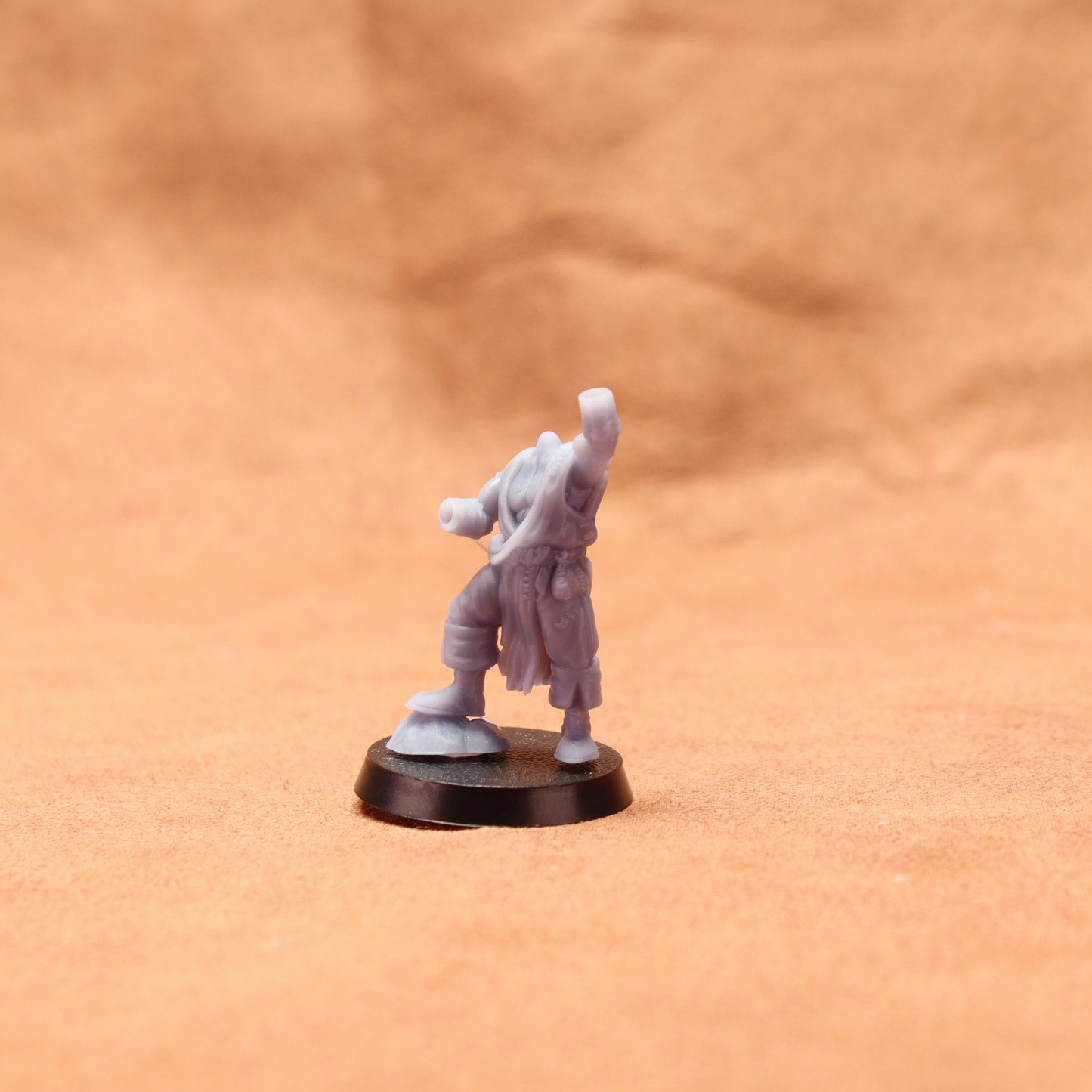 Gray miniature figure on a round base against a brown background