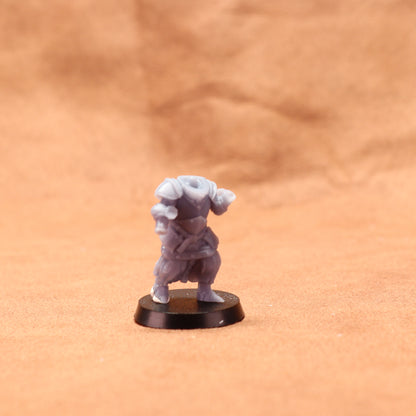 Small figurine on a round black base against a brown background