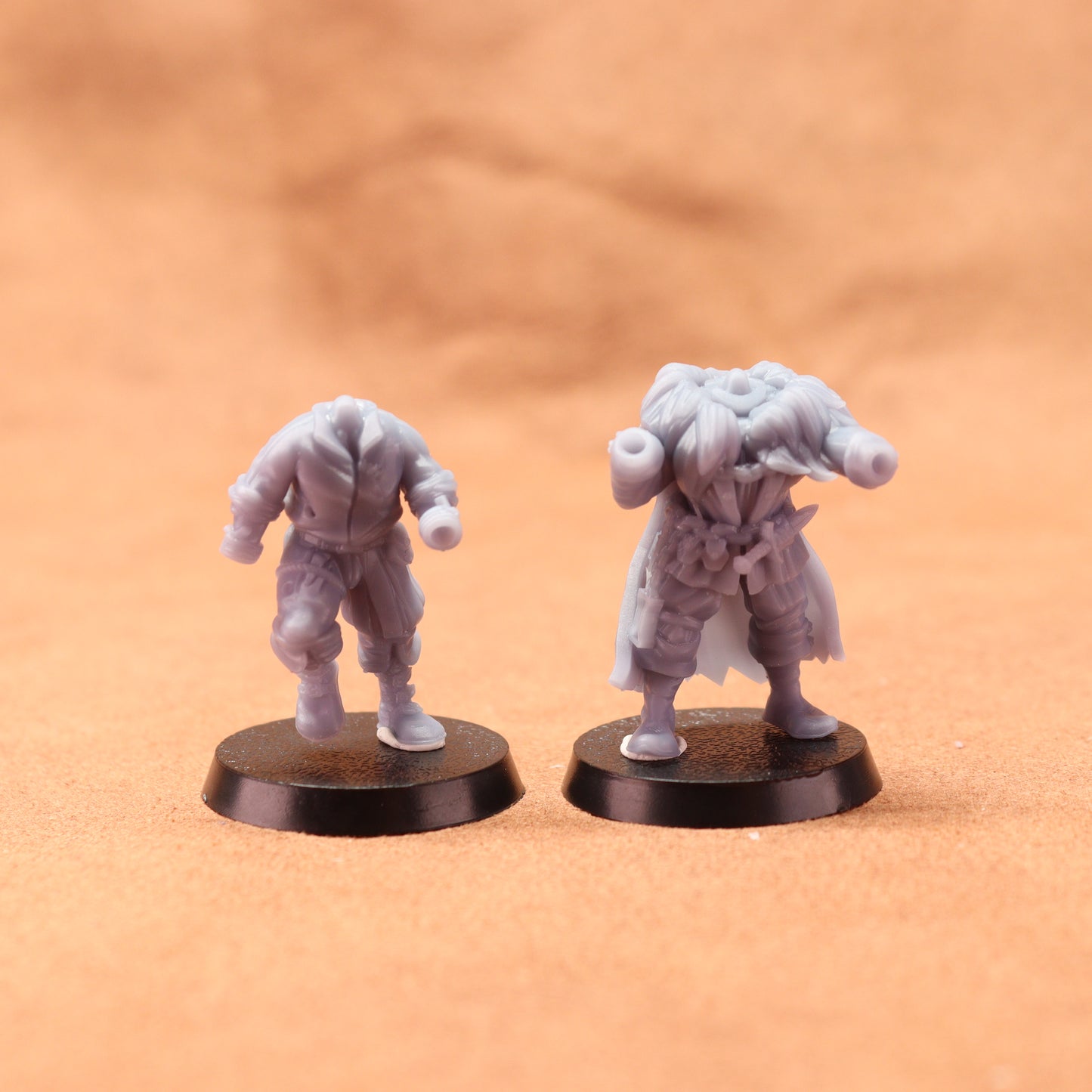 Two miniature figurines on round bases against a brown background