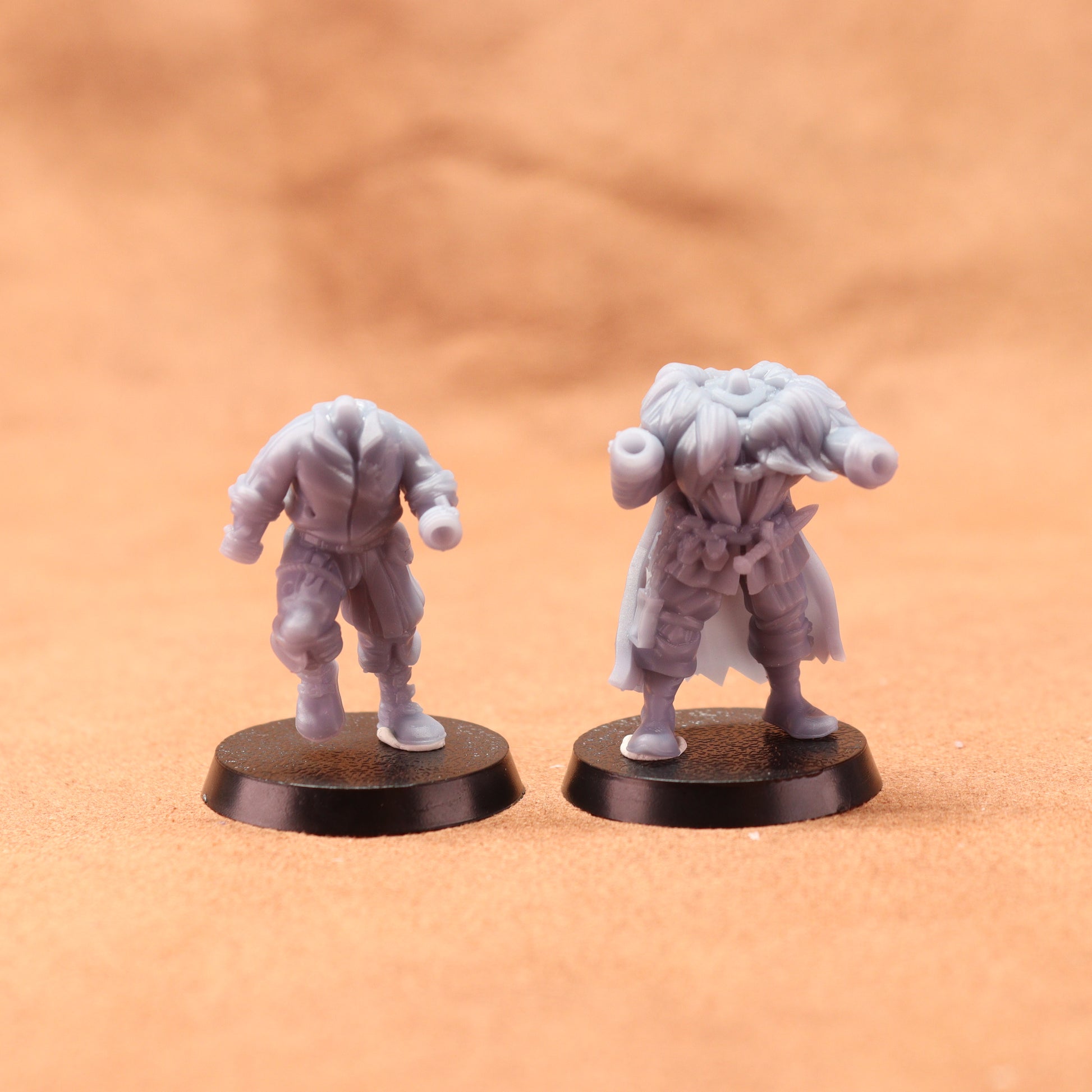 Two miniature figurines on round bases against a brown background