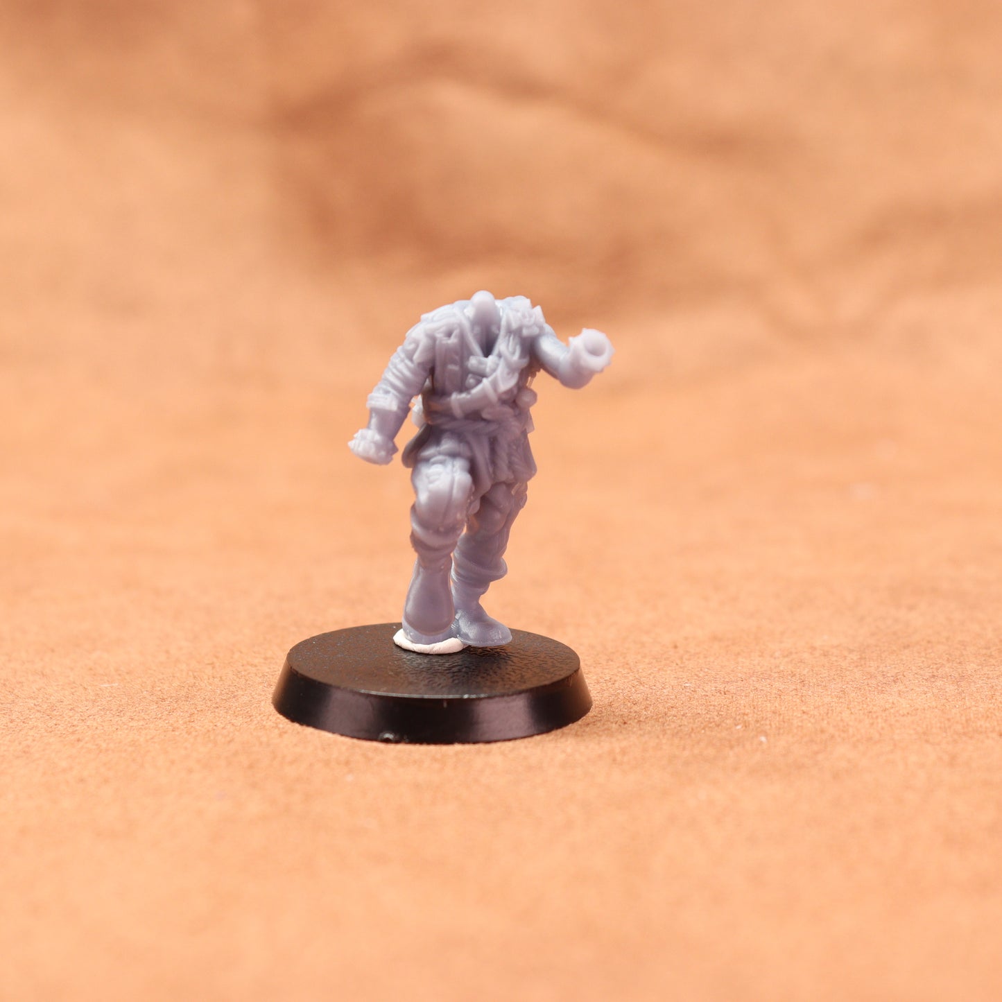 White miniature figure on a black base against an orange background