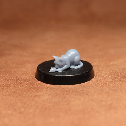 Small figurine of a cat on a round black base against a brown background