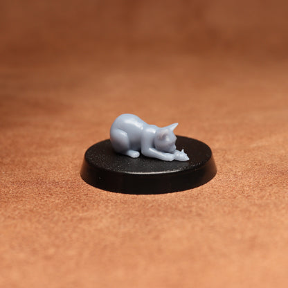 Small gray cat figurine on a black round base against a brown background