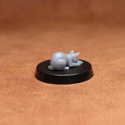 Small figurine of a cat on a black base against a brown background
