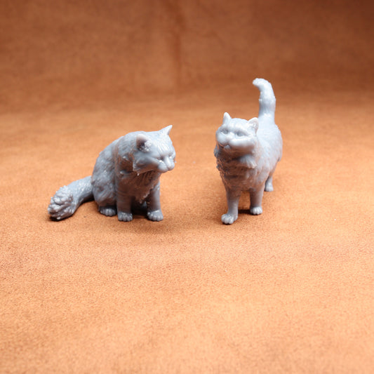 Two small cat figurines on a textured orange surface