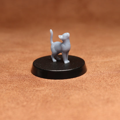 Small gray cat figurine on a black round base against a brown background