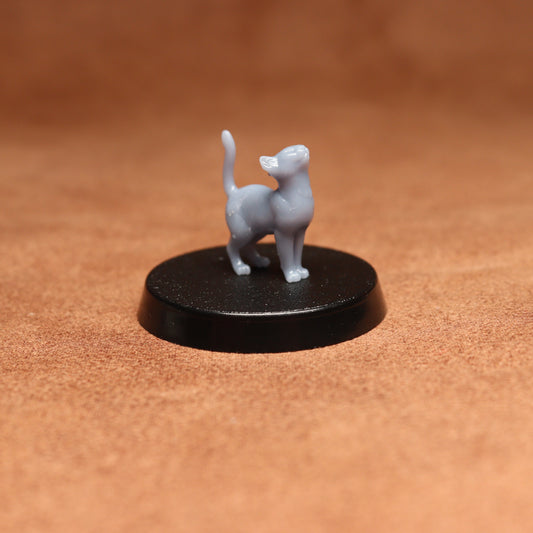 Small gray cat figurine on a black round base against a brown background