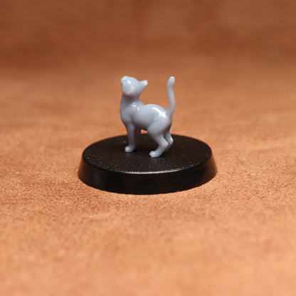 Small white cat figurine on a black round base against a brown background