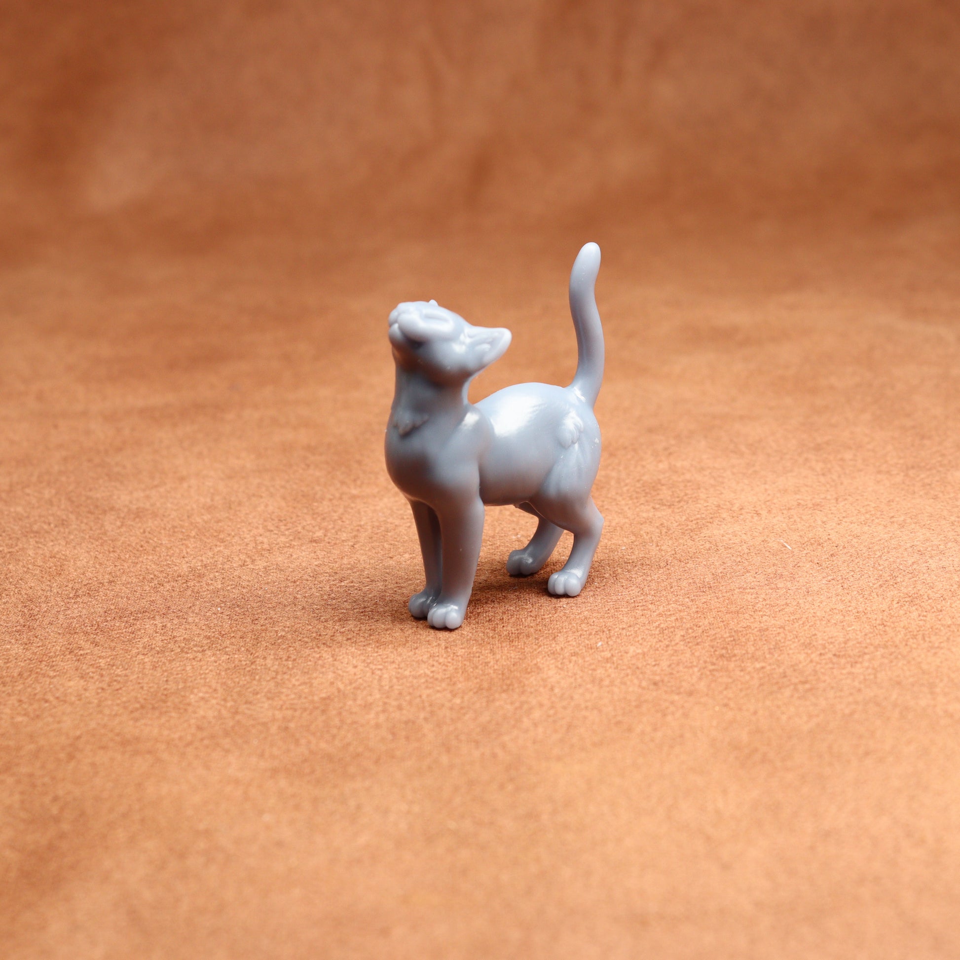 grey resin miniature cat figure on a brown surface
