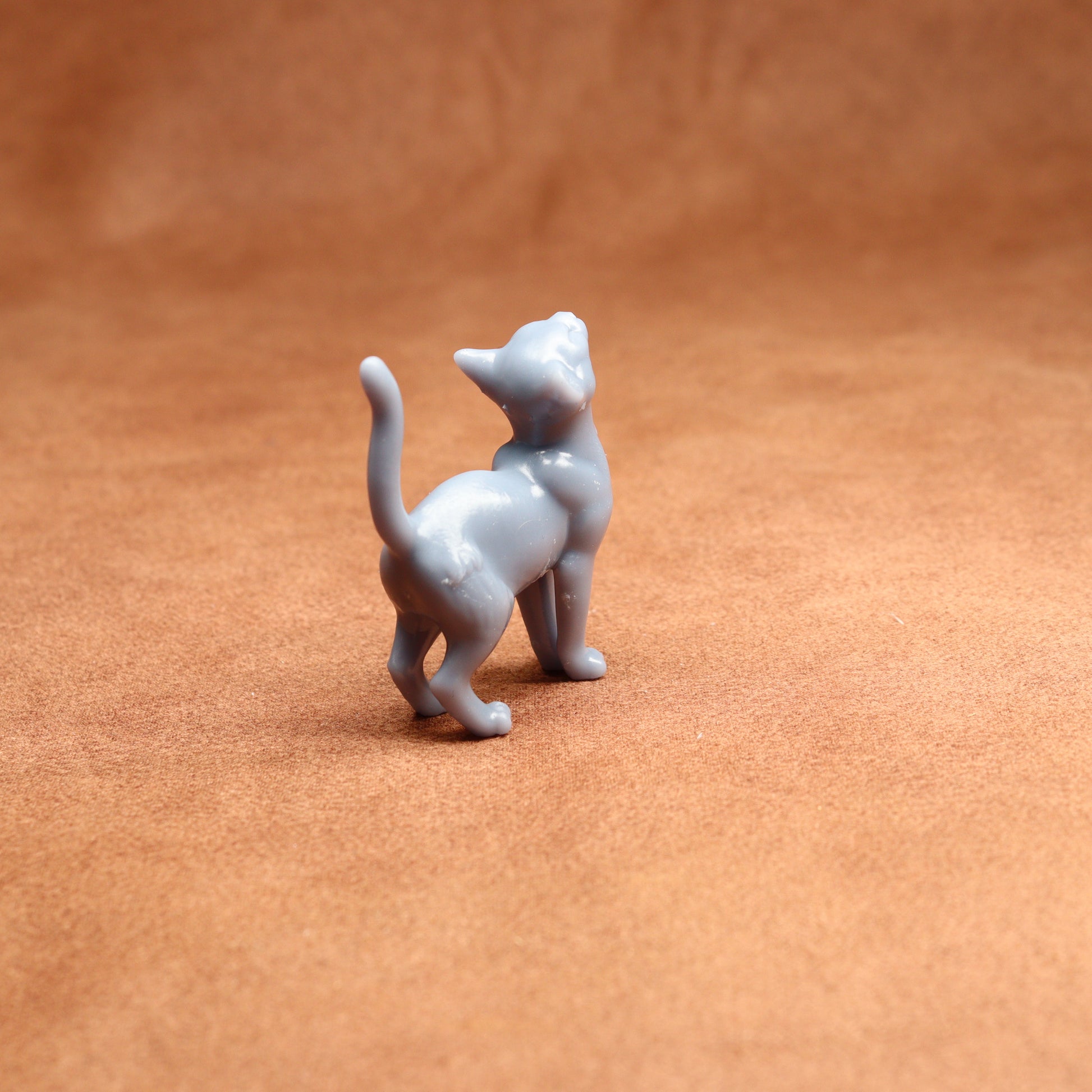 Small gray cat figurine on a brown surface