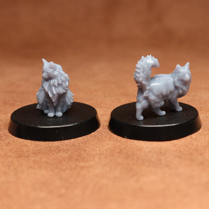 Two miniature cat figurines on black bases against a brown background