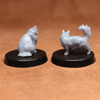Two miniature cat figurines on black bases against a brown background