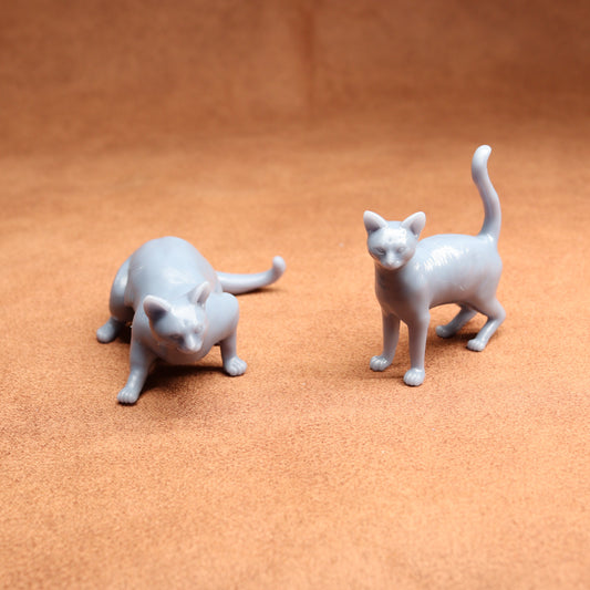 Two gray cat figurines on a brown surface