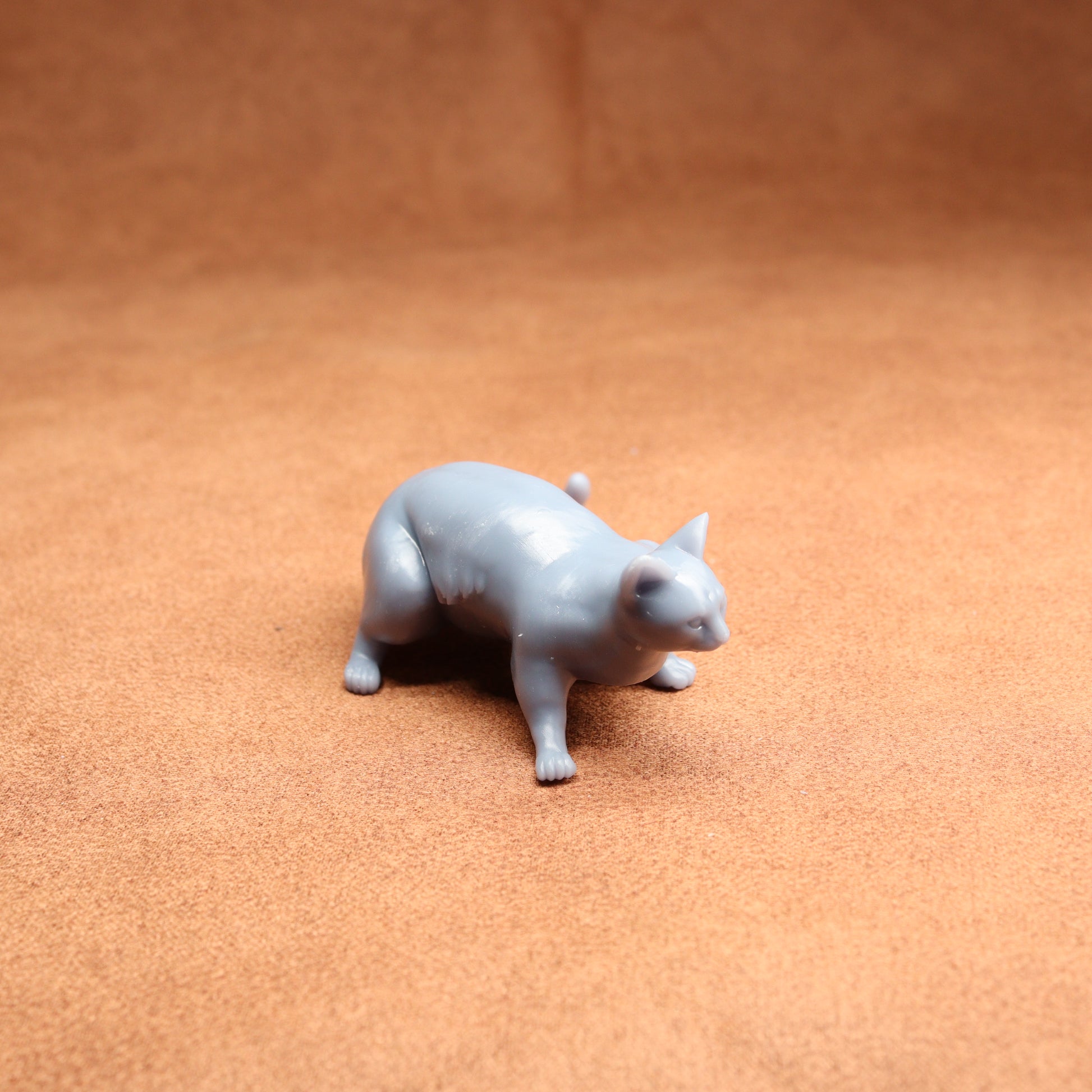 Gray cat figurine on a brown surface