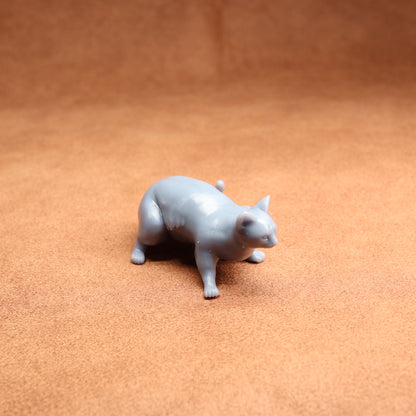 Gray cat figurine on a brown surface