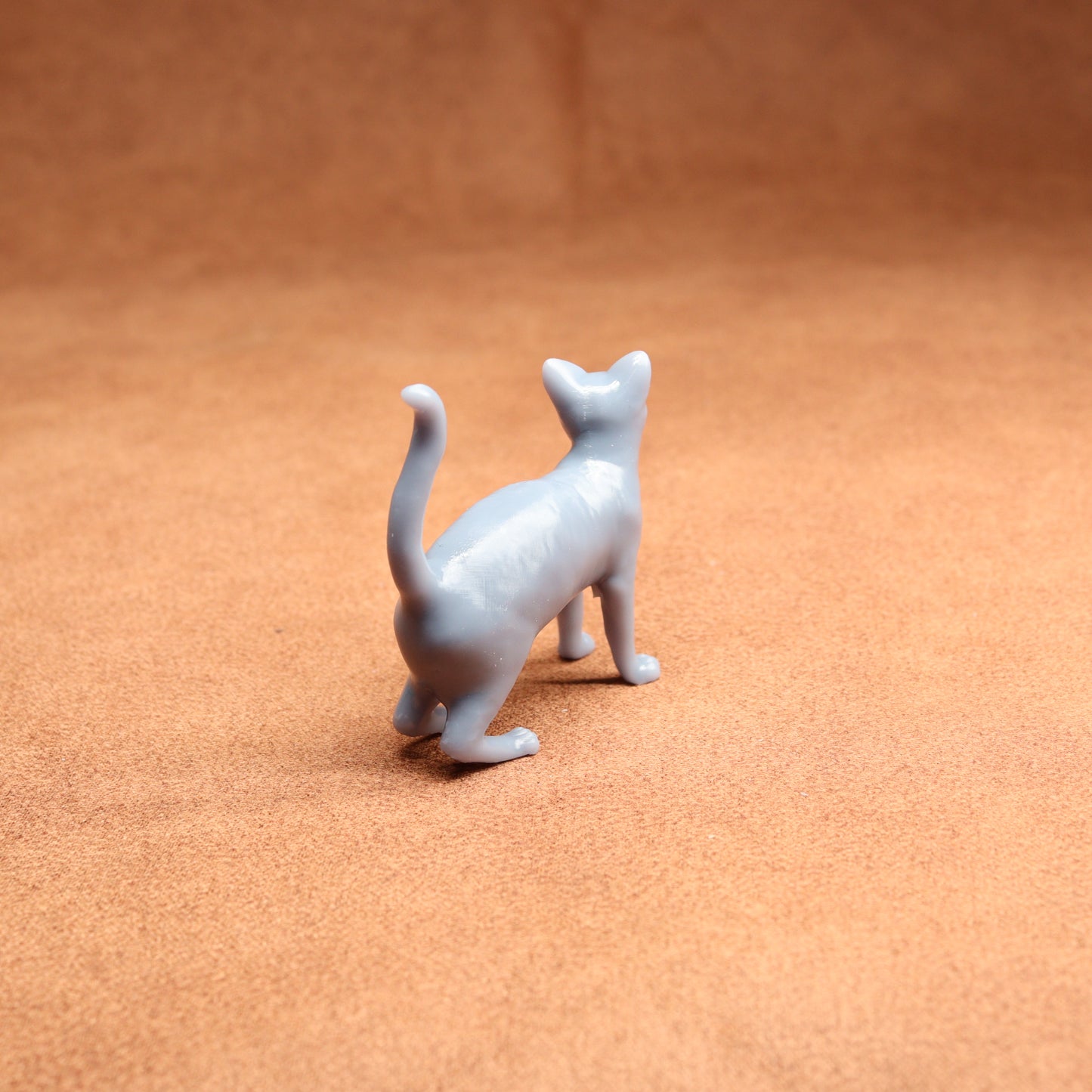 Small gray cat figurine on a brown surface