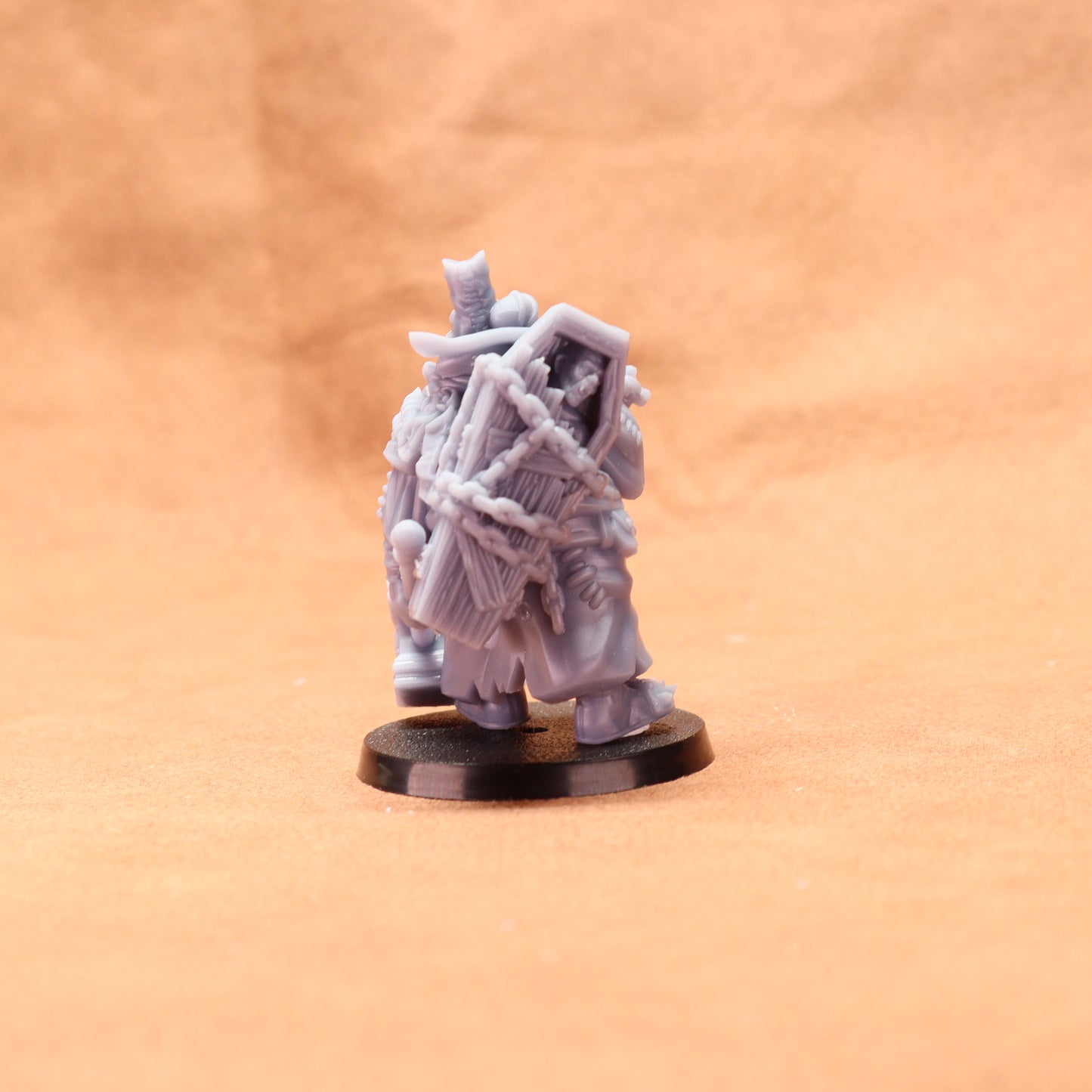 Gray miniature figure on a black base against a beige background