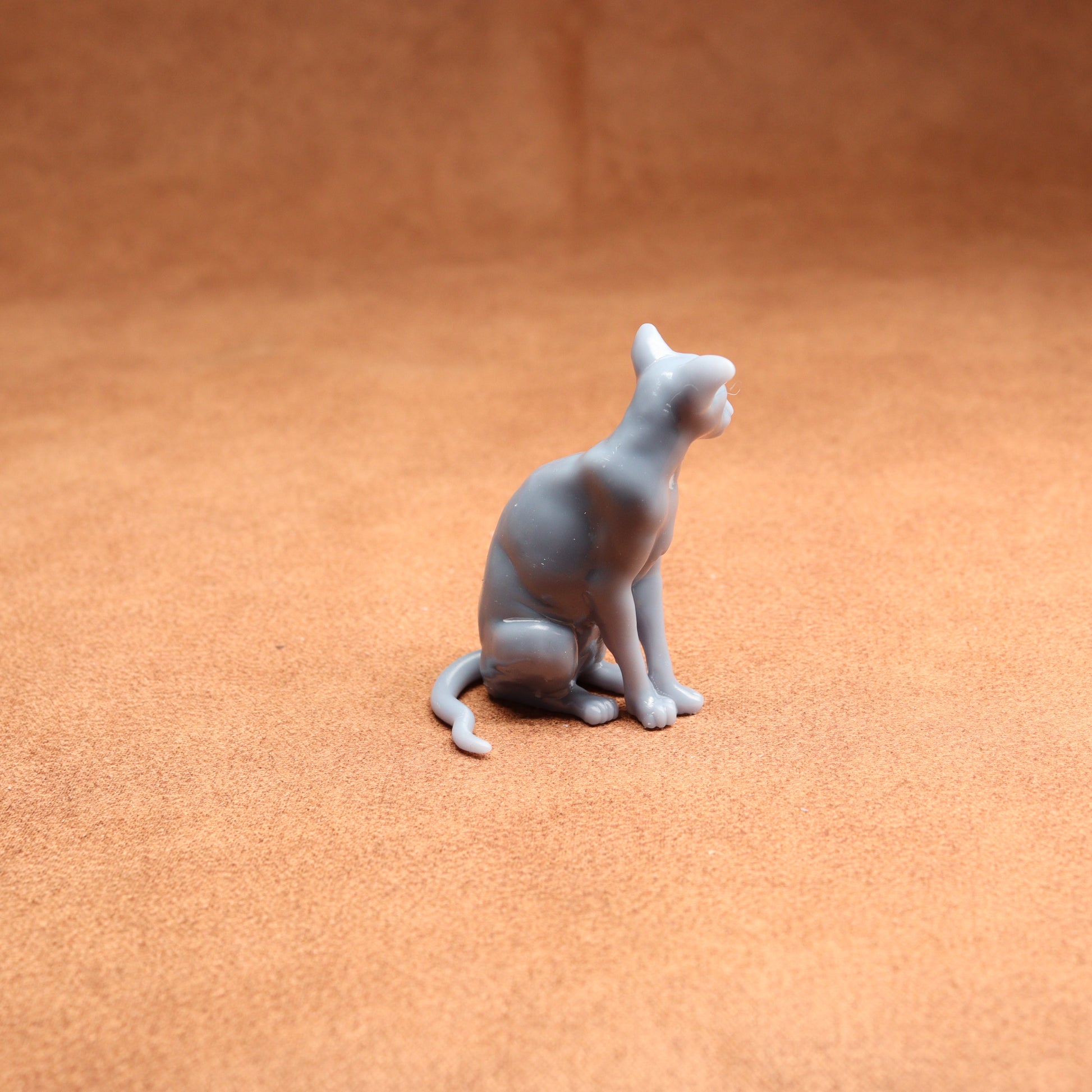 Gray cat figurine on a textured brown surface