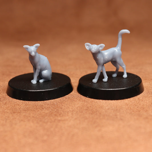 Two small white cat figurines on black bases against a brown background