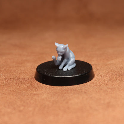 Small gray cat figurine on a black round base against a brown background