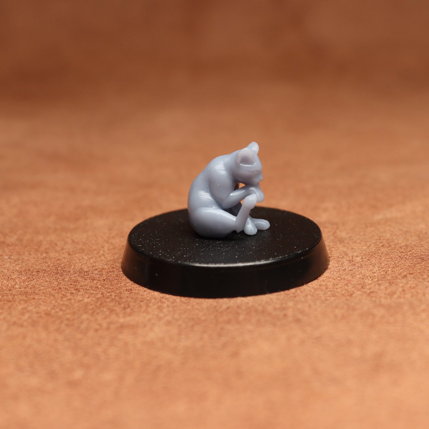 Small figurine of a cat on a black base against a brown background