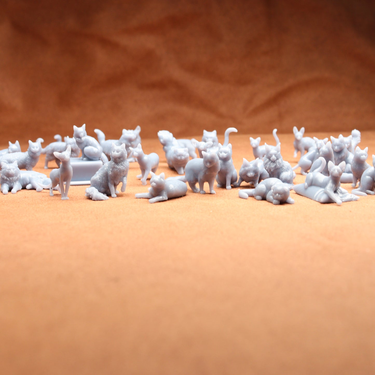 grey miniature resin cat figures on a brown background.