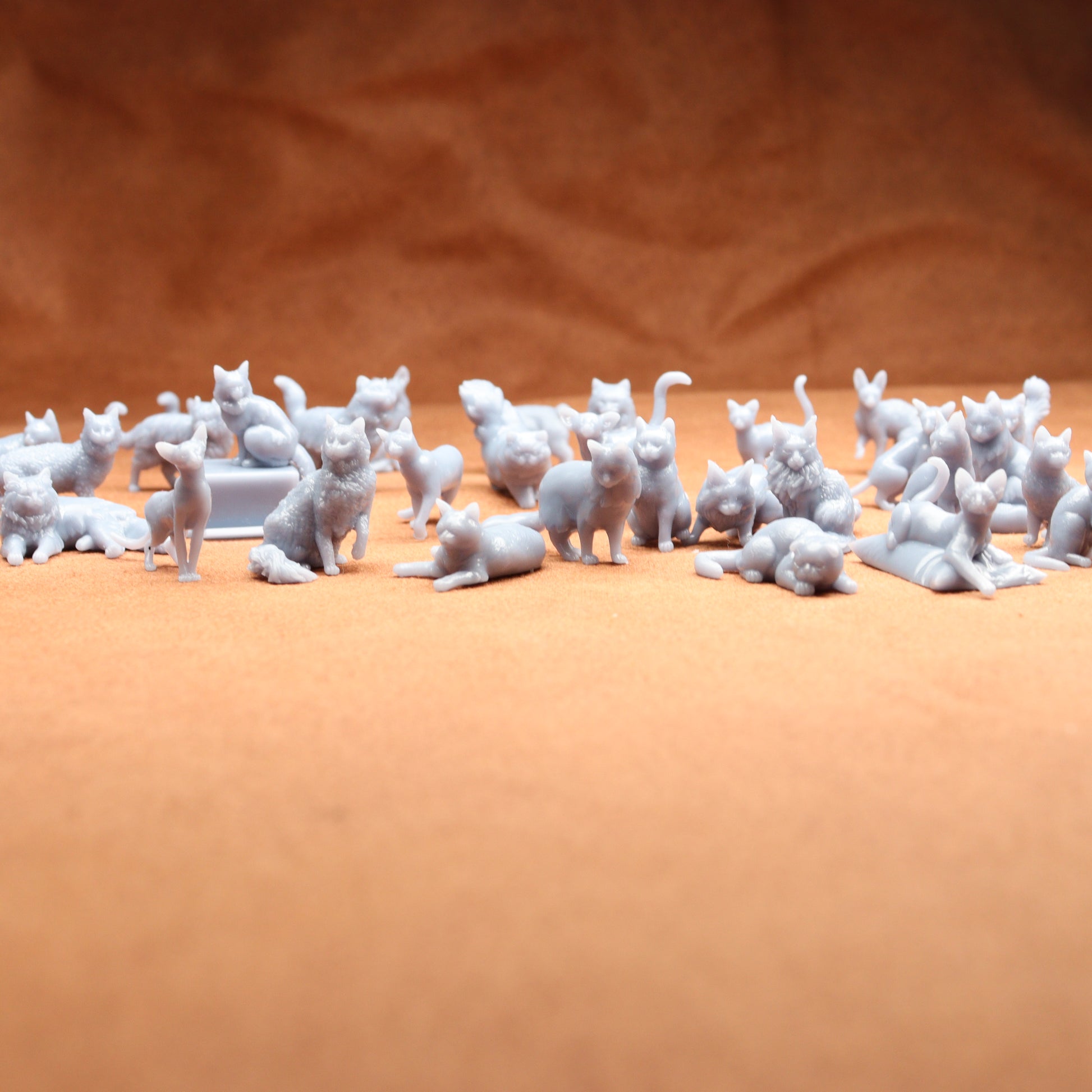 grey miniature resin cat figures on a brown background.